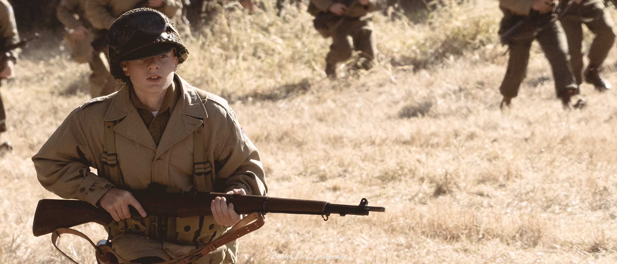 "A young World War II soldier stands confidently, gripping his M1 Garand rifle with a look of determination. Dressed in a standard military uniform, complete with a helmet and gear, he embodies the spirit of youth amidst the challenges of war. The background features a blurred battlefield, hinting at the chaos around him, while his focused expression conveys a sense of resolve and bravery. This poignant image captures the essence of the young men who fought during this tumultuous time, symbolizing courage and sacrifice."